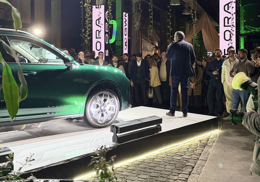 Presentación de un auto sobre un escenario en la nave de Flex, con luces, vegetación y público