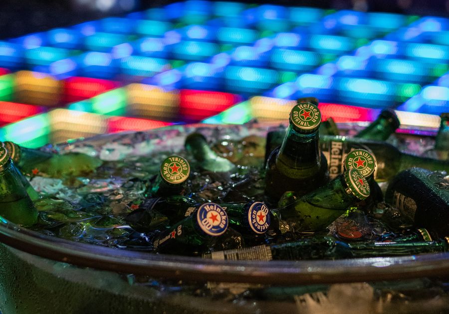 Hielera con botellas frente a una pista de baile con luces de colores, en una fiesta en Flex